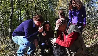 A group of guests smelling a freshly found truffle during a guided truffle hunt with an expert hunter and trained dog in Tuscany.